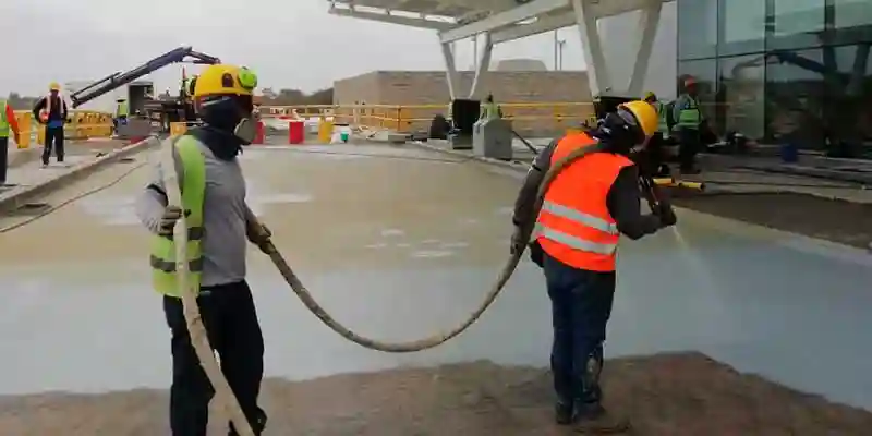 obreros regando suelo pra aplicar cocncreto